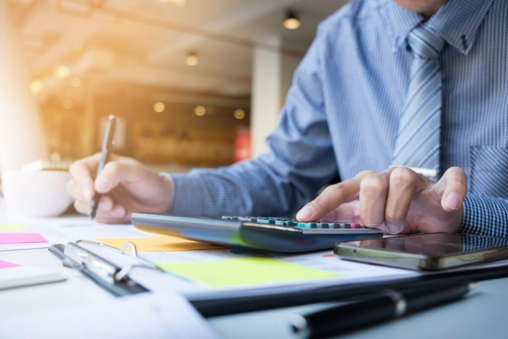 Man in suit working through taxes and using calculator at desk.