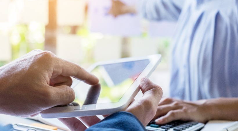 Person using work and financial software on a tablet.