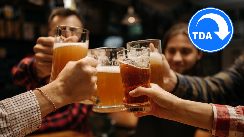 Friends clinking drinks together in a pub with the TDA logo