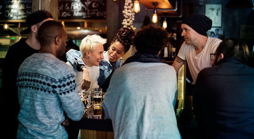 Young people gathering and celebrating in pub area.